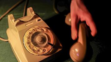 Closeup hands of man carefully places receiver of a vintage telephone in cradle photo