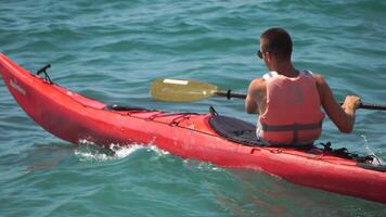 homme kayak mer. fort athlétique homme apprend à pagayer kayak dans ouvert mer océan sur ensoleillé journée. été vacances vacances et Voyage concept. aérien voir. lent mouvement video