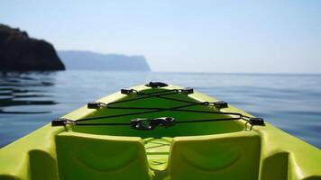 Sea water surface. Camera flies over the calm azure sea with green kayak boat on foreground. Nobody. Holiday recreation concept. Abstract nautical summer ocean nature. Slow motion. Close up video
