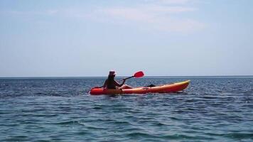 mulher mar caiaque. feliz sorridente mulher remar dentro caiaque em oceano. calma mar água e horizonte dentro fundo. ativo estilo de vida às mar. verão período de férias. video