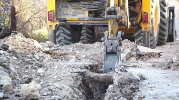 Excavator digs a trench to lay pipes. Close up of an excavator digging a deep trench. An excavator digs a trench in the countryside to lay a water pipe. Slow motion video