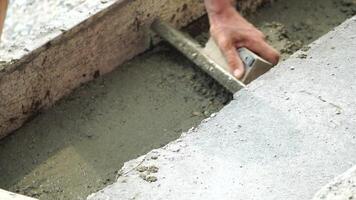 Construction, Worker Hands smooth wet cement in wooden frame at a construction site during daytime to ensure an even surface video