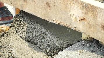 Construction, Worker Hands smooth wet cement in wooden frame at a construction site during daytime to ensure an even surface video