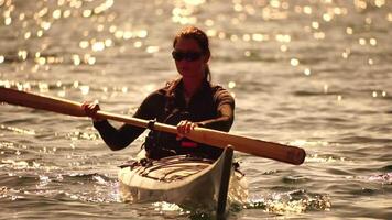 donna mare kayak. contento sorridente donna nel kayak su oceano, paddling con di legno remo. calma mare acqua e orizzonte nel sfondo. attivo stile di vita a mare. estate vacanza. video