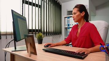 Leader writing on computer sitting alone in modern office room. Hispanic entrepreneur comming at work, in professional company workspace typing on computer keyboard looking at desktop video