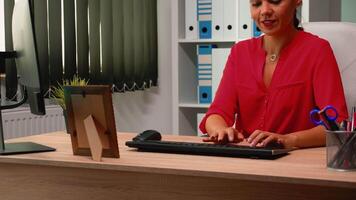 Business lady working alone at job on computer in office modern room. Hispanic entrepreneur sitting in professional company workspace typing on pc keyboard looking at desktop reading reports video