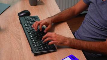 Close up of man's hands typing on keyboard sitting on chair in front of computer. Busy entrepreneur in new normal office workplace corporate writing on computer keyboard looking at desktop video