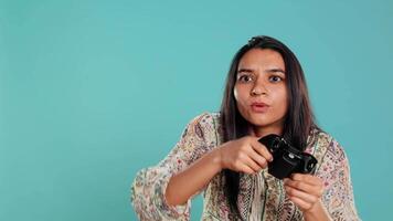 Upset woman showing thumbs down sign gesturing holding controller, after being defeated in videogames. Displeased indian person doing rejection hand gesture after losing, studio background, camera B video