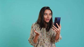 irritado mujer luchando con amigos durante teléfono inteligente videollamada, aislado terminado estudio antecedentes. indignado persona discutiendo con compañeros durante conversacion en móvil teléfono, cámara un video