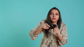 Happy gamer celebrating after winning game on gaming console, studio background. Delighted woman bragging after being victorious in videogame, defeating all enemies using gamepad, camera A video