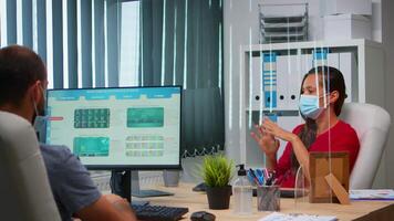 Woman with protection mask having online meeting conference in modern new normal office. Freelancer working in workplace chatting with remotely team during virtual webinar using internet technology video