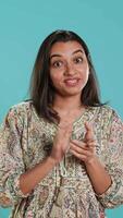 verticaal portret van jaloers Indisch vrouw spottend klappen handen, geïsoleerd over- studio achtergrond. geërgerd persoon rollend ogen en applaudisseren in grap, aan het doen nep juichen, camera een video