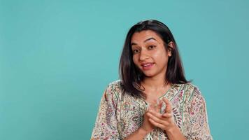 Portrait of jealous indian woman mockingly clapping hands, isolated over studio background. Annoyed person rolling eyes and applauding in jest, doing fake cheering, camera B video