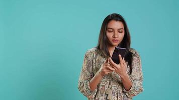 Indisch vrouw vegen Aan smartphone touch screen naar antwoord telefoon telefoontje van vriend, geïsoleerd over- studio achtergrond. portret van persoon luisteren en akkoord gaan met maat gedurende telefoon telefoongesprek, camera een video