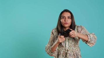 Upset woman showing thumbs down sign gesturing holding controller after being defeated in videogames. Displeased indian person doing rejection hand gesture after losing, studio background, camera A video