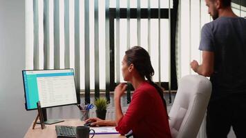 Young coworkers working together in modern office. Team discussing, talking, briefing consulting in professional, workplace in personal corporate company typing on computer keyboard looking at desktop video