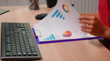 Close up of woman typing on keyboard sitting at desk and reading on clipboard. Entrepreneur working in professional company workspace typing on computer keyboard looking at desktop video