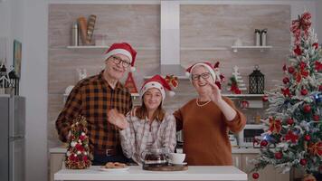 pov van familie vervelend de kerstman hoeden groet vrienden gedurende online videogesprek vergadering conferentie genieten van december seizoen. grootouders zittend Bij tafel in Kerstmis versierd culinaire keuken video