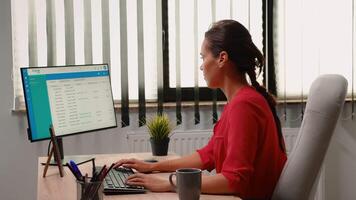 Woman administrator working alone in workplace in front of computer. Hispanic entrepreneur sitting in professional company workspace typing on computer keyboard looking at desktop reading reports video