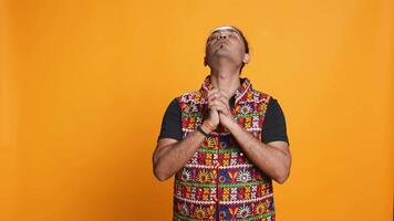 Indian man putting hands together in begging gesture, making wish, isolated over studio background. Faithful person asking for something, praying and hoping, believing in higher power, camera B video