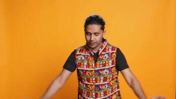 Happy indian person having fun, dancing on rhythm, enjoying leisure time. Cheerful man entertaining himself doing funky movements, isolated over studio background, camera B video