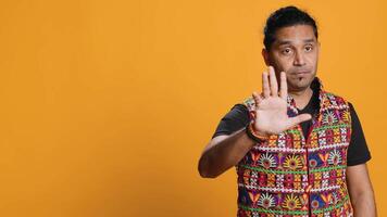 Stern indian man doing stop hand gesture sign, complaining. Authoritative person doing firm halt sign gesturing, wishing to end concept, isolated over studio background, camera A video