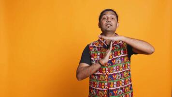 Portrait of assertive indian man asking for timeout, doing hand gestures, feeling fatigued. Firm person doing vehement pause sign gesturing, wishing for break, studio background, camera B video