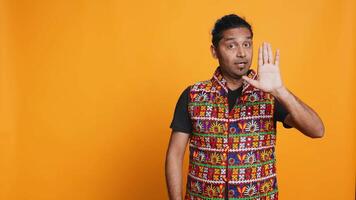 Stern indian man doing stop hand gesture sign, complaining. Authoritative person doing firm halt sign gesturing, wishing to end concept, isolated over studio background, camera B video