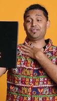 Vertical Radiant man saluting friend over online videocall, doing friendly gestures. Joyful person communicating with mate on teleconference using tablet, studio background, camera A video