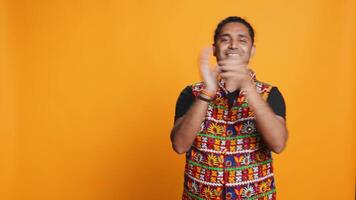 Joyful indian man happily clapping hands, ecstatic about accomplishments. Excited person reacting to good news, cheering, applauding, isolated over studio background, camera B video