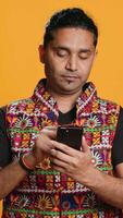 Vertikale indisch Mann Hinzufügen Zahlung Methode auf Handy, Mobiltelefon Telefon Webseite, Einkauf Sachen, isoliert Über Studio Hintergrund. Klient tut Internet Einkaufen, Tippen Lastschrift Karte die Info auf Handy, Kamera ein video