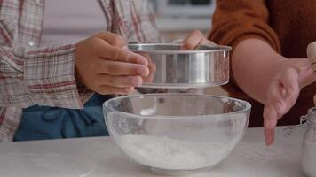 närbild av barnbarn anstränga mjöl ingrediens i kök skål framställning hemlagad kaka deg framställning traditionell utsökt efterrätt. familj njuter traditionell vinter- jul Semester video