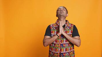Pious indian man praying to his god, asking for forgiveness. Spiritual person doing worship hand gesturing, confessing, begging for pardon, isolated over studio background, camera B video