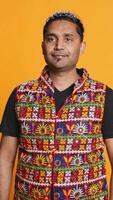Vertical Portrait of cheerful friendly indian man smiling, looking pleased, isolated over studio background. Happy expressive asian person in traditional attire grinning, feeling satisfied, camera B video