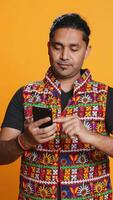 Vertical Happy man playing videogames on smartphone, celebrating after defeating foes, doing clenching hand gesture. Player swiping phone screen, thrilled about winning game, studio background, camera B video