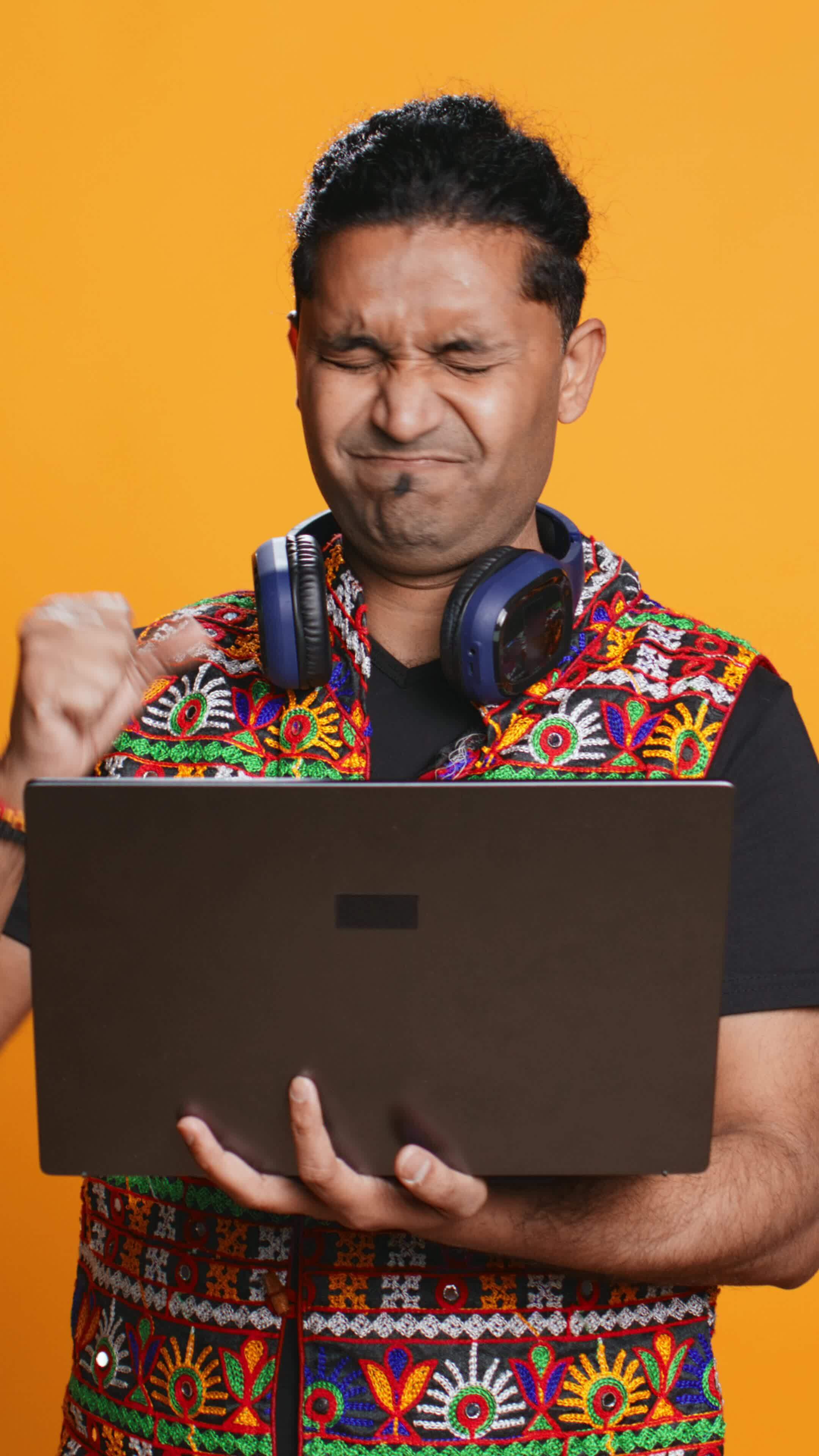 Vertical indian man composing email typing on laptop frustrated with