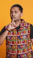 Vertical Annoyed indian man doing shushing hand gesturing, irritated by noise, having negative mood. Person placing finger on lips, doing quiet sign gesture, studio background, camera B video