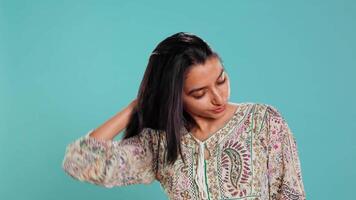 Portrait of cheerful friendly indian woman smiling, flipping long healthy hair, isolated over studio background. Happy brunette person confident with natural hairstyle, feeling satisfied, camera B video