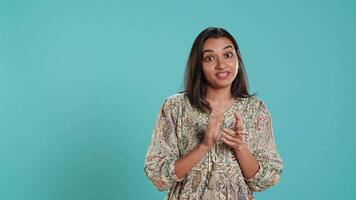 porträtt av svartsjuk indisk kvinna Mockingly applåder händer, isolerat över studio bakgrund. irriterad person rullande ögon och applåderar i skoj, håller på med falsk glädjande, kamera en video