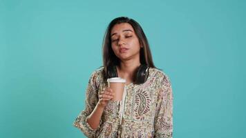 Sleepy woman yawning, sipping coffee to gain energy and get rid of headache. Exhausted person feeling fatigued after sleepless night, drinking caffeinated beverage, studio backdrop, camera A video