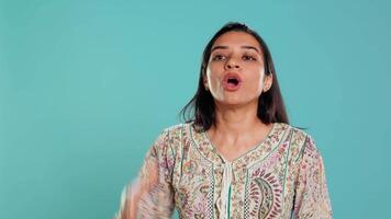 Portrait of joyful indian woman celebrating, showing positive emotions, feeling happy. Delighted person thrilled by achievement, cheering and gesticulating, studio background, camera B video