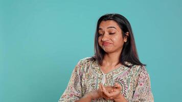 Portrait of envious indian woman mockingly clapping hands, showing frustration, studio backdrop. Resentful sassy person rolling eyes and applauding in jest, feeling irritated, camera B video