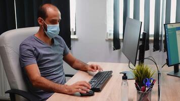 lavoratore indossare protezione maschera utilizzando disinfettante per corona virus protezione seduta nel nuovo normale ufficio camera. imprenditore Lavorando nel moderno posto di lavoro pulizia mani utilizzando antibatterico alcool video