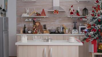 Empty xmas decorated culinary kitchen with nobody in it is ready for traditional christmas celebration. On table standing traditional homemade cookie dessert ingredients with milk glass video