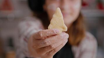 selektiv fokus av barn innehav kaka deg med träd form i händer framställning hemlagad traditionell pepparkaka njuter matlagning efterrätt i kulinariska kök. flicka njuter jul Semester video