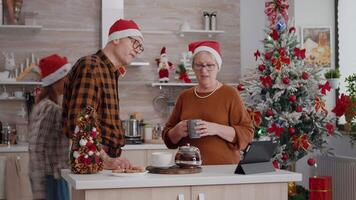 abuelos con nieta gasto hora juntos disfrutando invierno temporada que se discute con remoto amigos durante en línea videollamada reunión en tableta. familia celebrando Navidad fiesta video