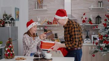 petite fille avec grand-père partage Noël emballage présent cadeau avec ruban sur il profiter période de Noël pendant hiver vacances. content famille célébrer Noël dans décoré cuisine video