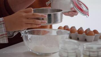 de cerca de abuela poniendo harina ingrediente en colador mientras nieto preparando tradicional invierno Galleta en culinario cocina. familia disfrutando Navidad Días festivos haciendo hecho en casa postre video