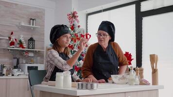 Enkelkinder tragen Schürze während vorbereiten köstlich hausgemacht Lebkuchen mit Weihnachten Kekse gestalten im kulinarisch Küche. glücklich Familie genießen Weihnachten Urlaub Kochen traditionell Dessert video