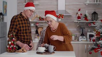 mormor sätta kaffe i kopp tjänande bakad utsökt choklad småkakor njuter vinter- säsong tillsammans. Lycklig familj fira jul Semester i xmas dekorerad kulinariska kök video